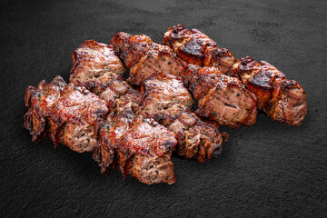 Grilled pork kebabs, handmade on a dark stone background. BBQ menu