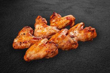 Grilled chicken wings on a dark stone background. BBQ menu