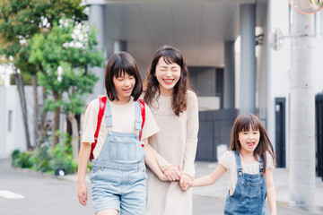 お母さんと手を繋いで学校に行く2人の女の子