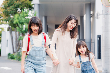 お母さんと手を繋いで学校に行く2人の女の子