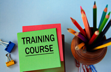 TRAINING COURSE - words on a green sheet for notes on the background of pencils and paper clips