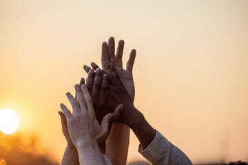 Witness the strength of unity and camaraderie among a diverse group of friends in this symbolic and powerful image. Silhouetted against the backdrop of shared joy, their hands are raised high in the