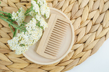 Wooden hairbrush (comb) and yarrow flowers. Eco friendly toiletries, natural hair care, homemade spa and beauty treatment recipe.