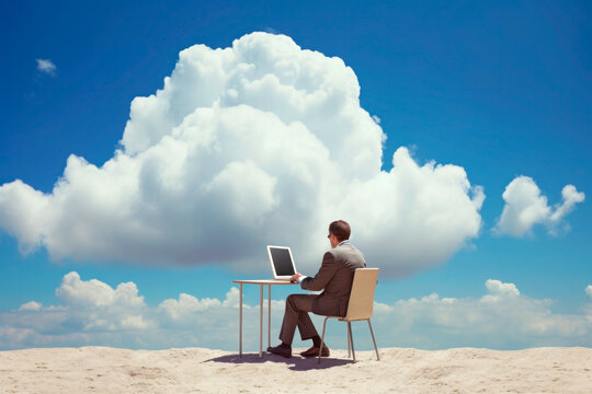 Back view of businessman sitting in clouds working with laptop on the desk