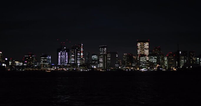 東京湾からみた夜景。暗い海に浮かんでいるように見える高層ビル群の光が美しい映像。
