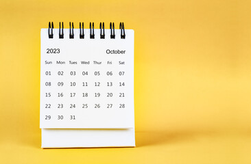 The October 2023 desk calendar on yellow color background.
