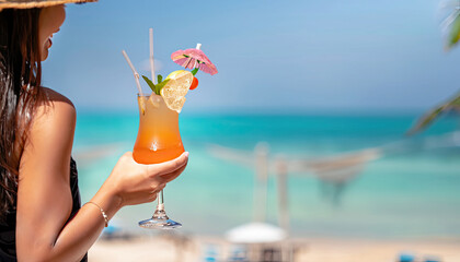 The girl hand lifting cocktail, tropical beach background blured. Copy space the in beach