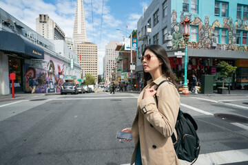 Fototapeta premium side view of asian Korean business woman wearing sunglasses passing by road intersection on her way to office in the financial district of san Francisco's Chinatown in California usa