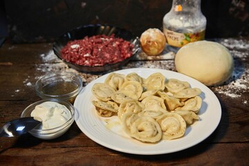 The dish is cooked dumplings. Handmade work. Slavic or Balkan cuisine. Sour cream sauce