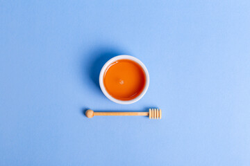Honey in white ceramic bowl from above on a blue background. 