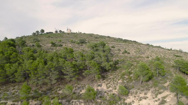 Fast 4K drone fly by over the ancient pair of rebuilt windmills on top of the hill in Alcublas, Spain