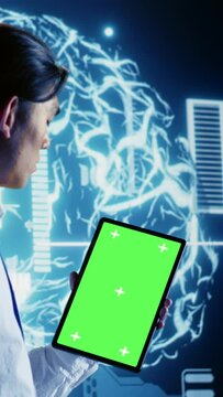Vertical video Tech savvy IT practitioner using green screen tablet to implement artificial intelligence parallel processing. Proactive inspector oversees chroma key device enabling AI to do machine