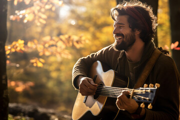 Cheerful young male musician performing for his fellow hikers on sunny fall day. Performer playing a guitar in the wild. People having fun on a hike in autumn.