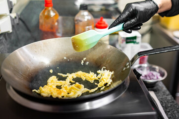 man chef cooking tasty scrambled eggs in wok frying pan on kitchen