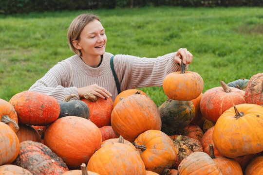 Young woman choosing pumpkins at farm shop.