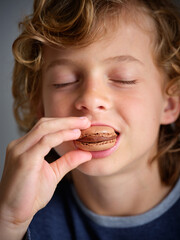 Boy eating sweet chocolate macaroon