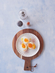 View from above, halves of hard-boiled eggs with olive oil and paprika. Salt and pepper shakers on...