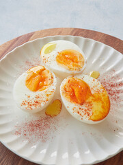 three halves of hard boiled eggs on a white plate with olive oil and paprika sprinkled on top. Healthy and protein food.