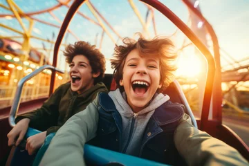 Foto auf Alu-Dibond Excited teenage children laughing and riding a carousel carnival ride merry-go-round in amusement park during festival. Family leisure with kids. © MNStudio
