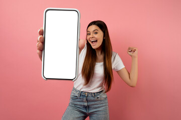 Emotional teen girl holding blank smartphone and celebrating success, mockup