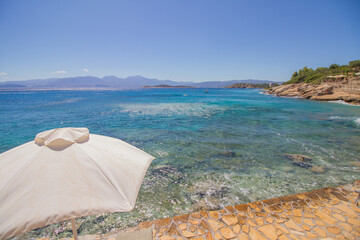 Shore of the turquoise mediterranean sea at the island of Crete, Greece, near Agios Nikolaos, with sunshade parasol, rocky coast