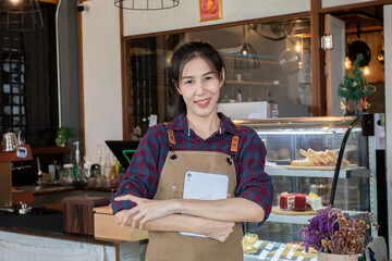 Asian beautiful woman standing holding tablet in front of the counter taking orders. Confident female succeeds her own small coffee shop business. restaurant entrepreneur concept.