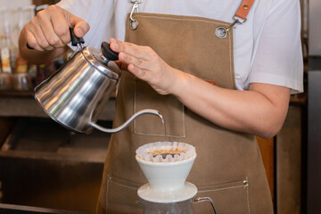 Professional barista pouring hot water from classic jar to arabica coffee in filter, concept of dipping coffee, Pour water into a cup for dipping coffee. Startup small business in cafe.