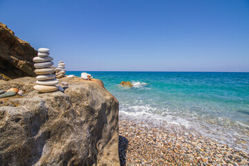 Small stone towers with turquoise sea at beach Geropotamos near Rethymno, island of Crete, Mediterranean Sea, Greece