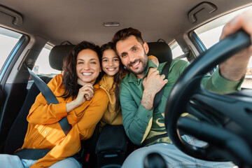 Automobile rent and purchase. Excited family embracing sitting in new car driving and enjoying road trip on vacation - obrazy, fototapety, plakaty