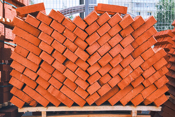 Stack of red building bricks close-up. Red bricks for laying at construction site. Brick wallpaper pattern.