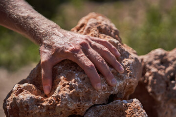 Crop man leaning on stone