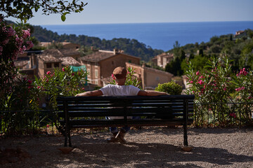 Man sitting on bench looking at old houses