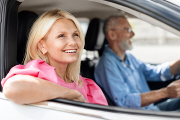 Cheerful senior couple travellers enjoying car trip together