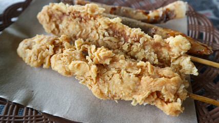 Crispy chicken tenders cuts on dark wooden background.