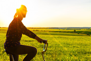 girl rides a bike outside the city in sunny weather