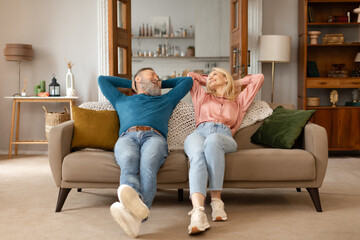 Happy Mature Couple Leaning On Couch Relaxing At Cozy Home