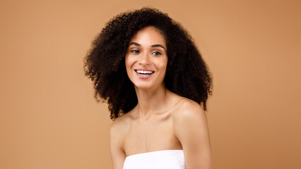 Natural beauty. Happy young latin lady with curly hair enjoying selfcare routine, posing over brown...