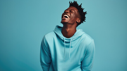 Fototapeta premium Young man laughs against a blue background.