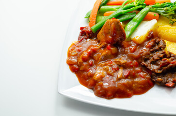 Pulled pork in barbecue style sauce with barbecues style beans with spiced chips and fresh vegetables