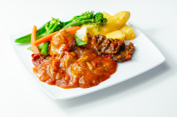Pulled pork in barbecue style sauce with barbecues style beans with spiced chips and fresh vegetables