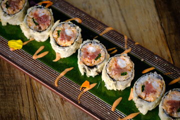 Delicious fried sushi with cream on tray over wooden table