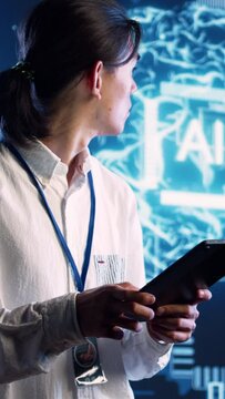 Vertical video Asian developer using tablet to implement artificial intelligence parallel processing, breaking up complex computational tasks into smaller bits, enabling AI systems to process more