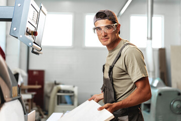 Fototapeta premium Male carpenter using some woodworking tools for his work in a factory