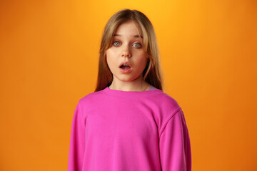 Fototapeta premium Surprised amazed teen girl against yellow background in studio