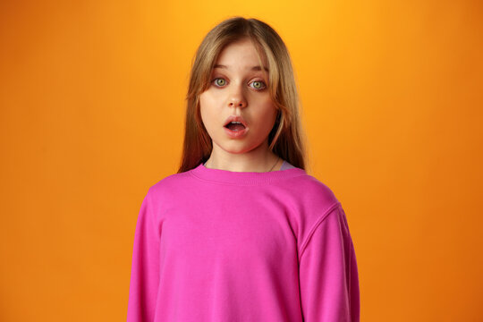 Surprised amazed teen girl against yellow background in studio