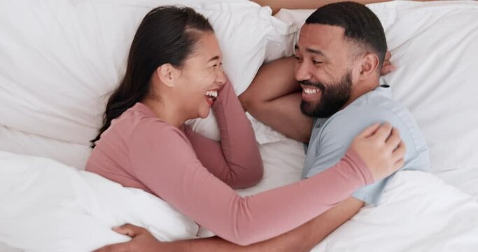 Happy couple, bed and laughing in funny morning, joke or relax together on holiday weekend or break above at home. Man and woman smile lying in bedroom happiness, wake up or humor in bonding at house