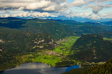 Scenic aerial panoramic view of Bohinj Lake with mountain range and valley with small village. Nature landscape during the autumn season. Travel and tourism concept. Triglav National Park, Slovenia