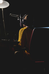 Unrecognizable ethnic woman in headset in dark broadcast studio