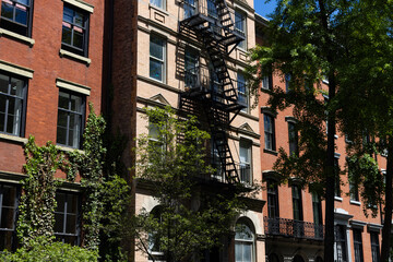 Fototapeta na wymiar Row of Beautiful Old Brick Apartment Buildings along a Street in the East Village of New York City with Green Trees