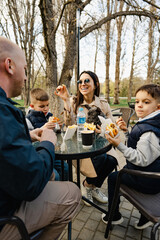 Happy family with two kids having a sancak at outdoor cafe on autumn day